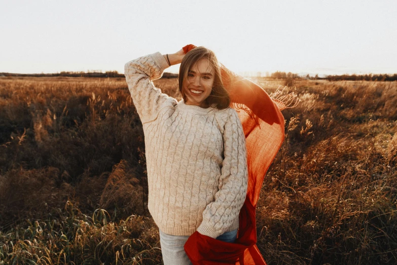 a smiling woman is holding her hand behind her head