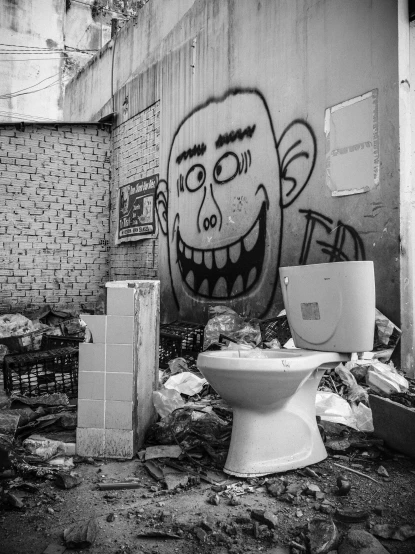 a trash can is on the ground next to a graffiti covered toilet
