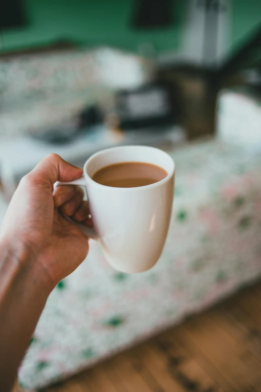 hand holding coffee mug, with table in the background