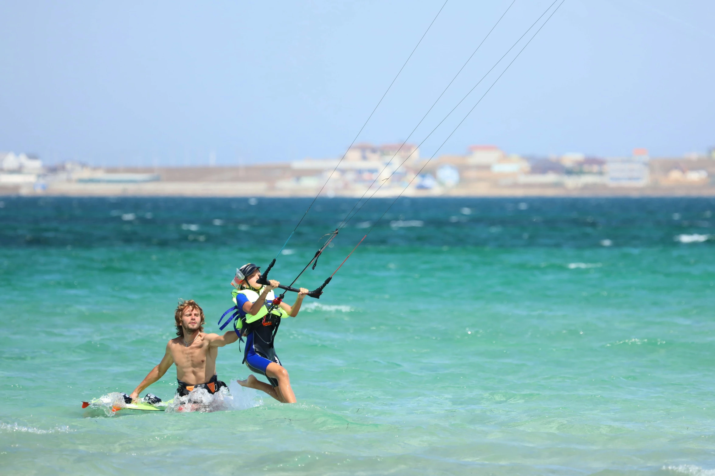 a couple people standing in the water with a parachute