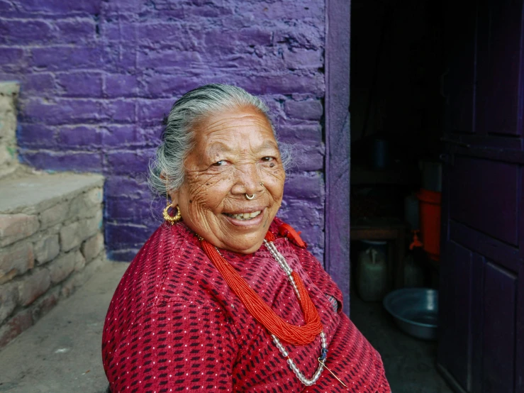 an older woman stands in front of a purple building