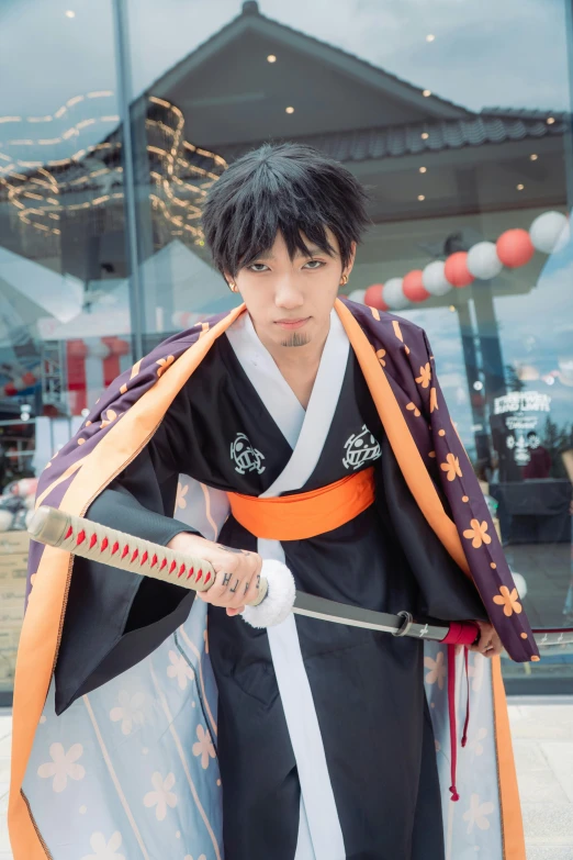 man in black and orange kimono holding a sword