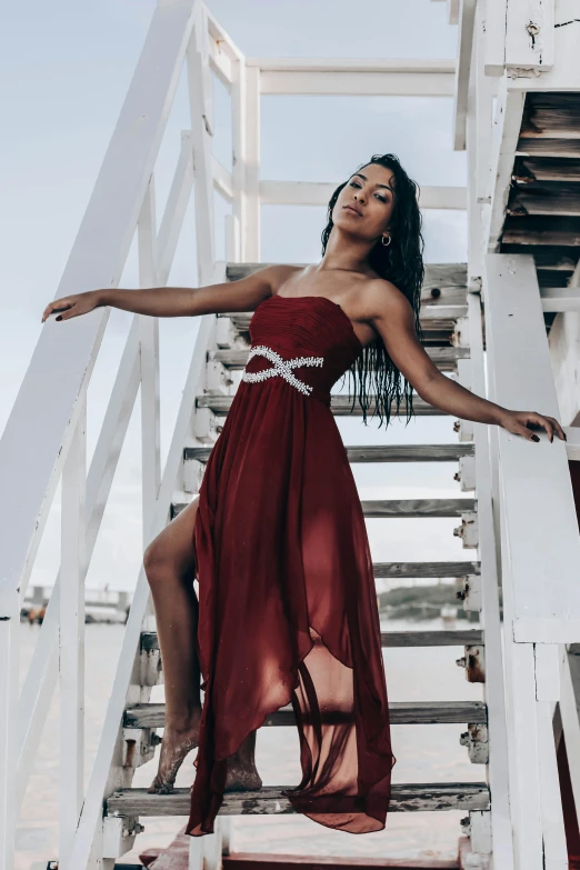 a young black woman is standing on stairs wearing a long red dress