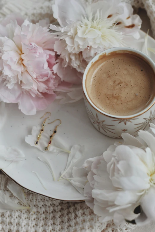 a coffee cup surrounded by flowers on top of a white saucer