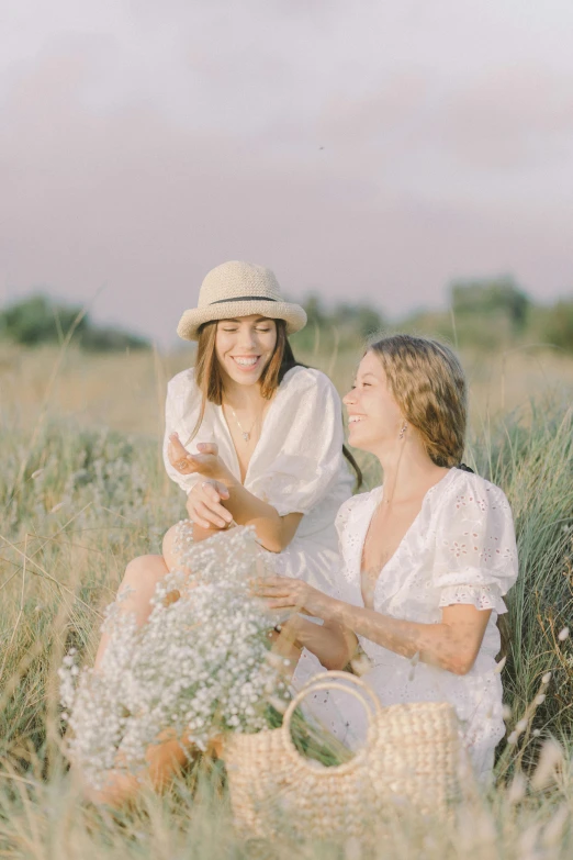 two women sit together in a wheat field