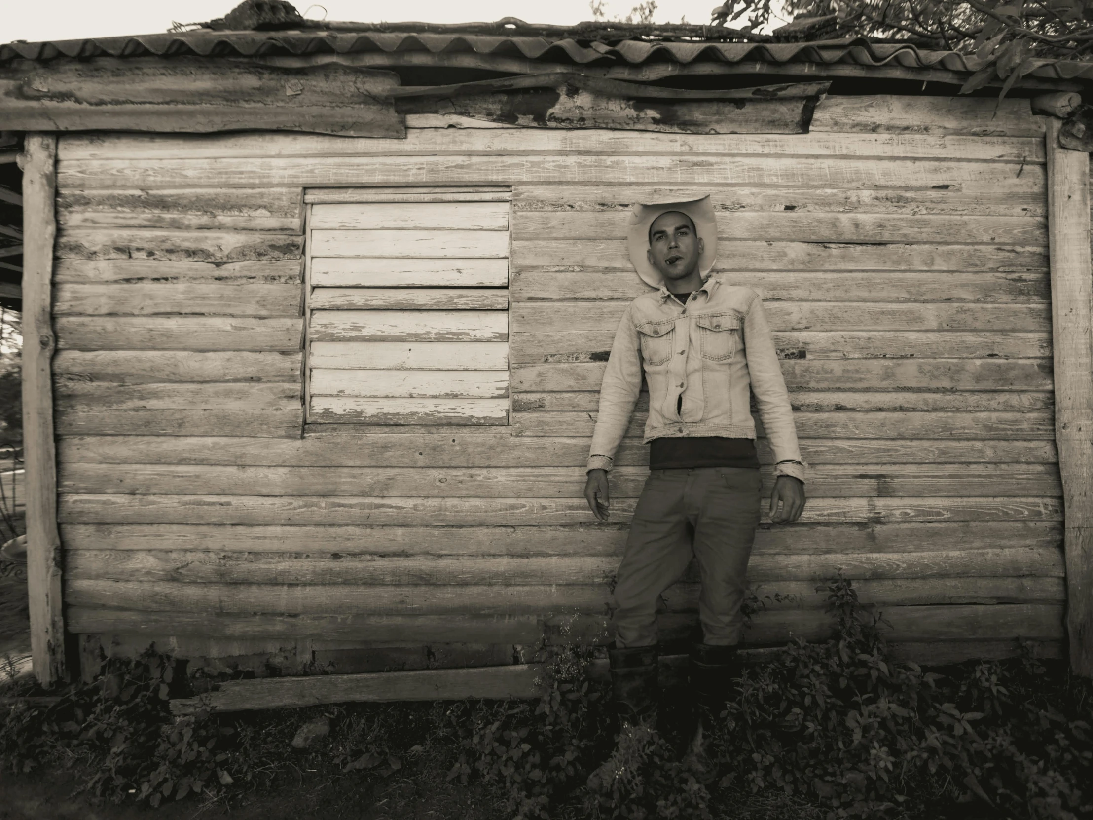 a man wearing a white jacket and brown pants standing next to a building