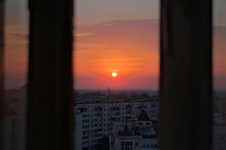 the sun setting over a city seen through the windows