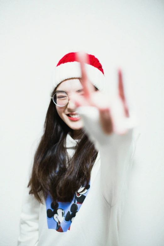girl wearing a santa hat and glasses making a gesture