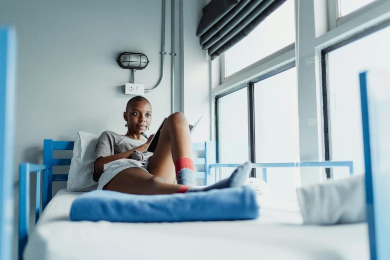 a man sitting on a bed next to a window