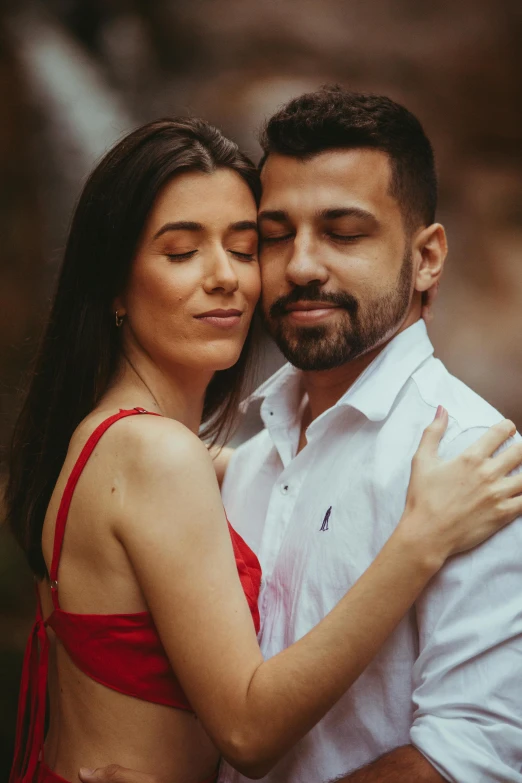 a woman wearing a red dress hugs a man wearing a white shirt