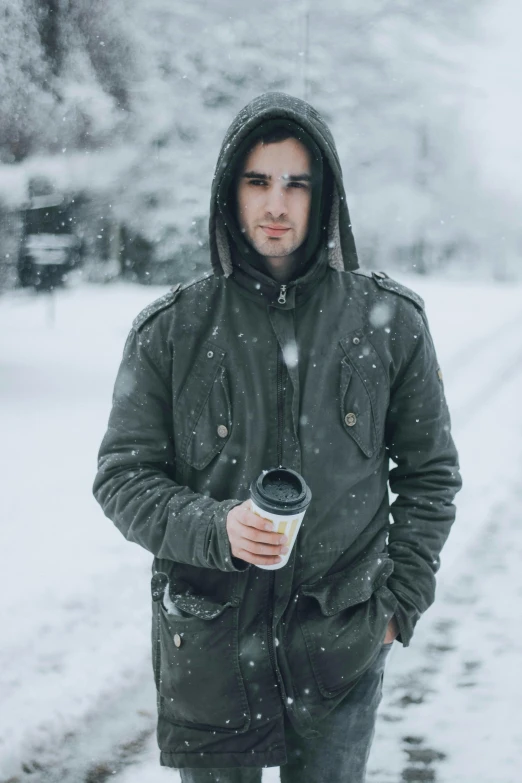 man holding coffee in front of road during winter