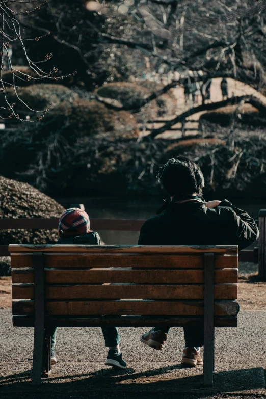 two people are sitting on a park bench