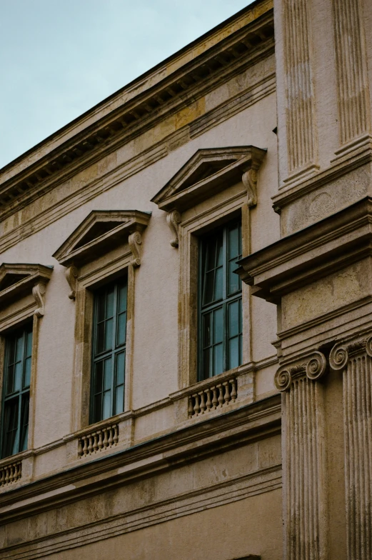 a large tan and black clock some windows and a tan building