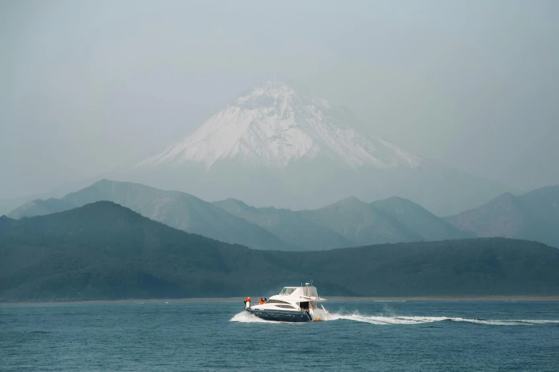 a large boat speeds past a mountain range