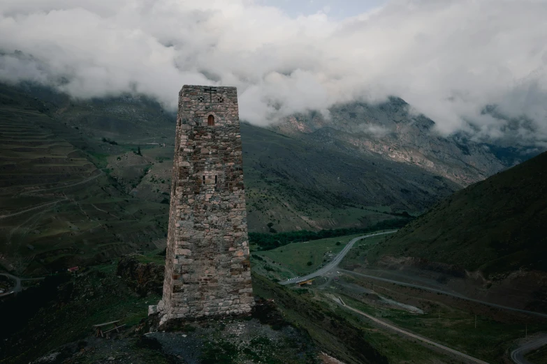 a tall brick tower stands on top of a grassy hill