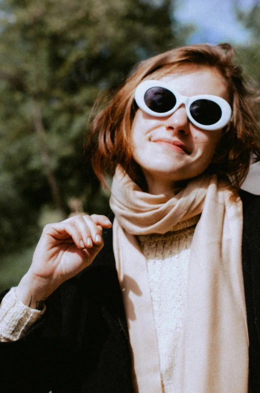 the woman wears oversized white sunglasses and a scarf