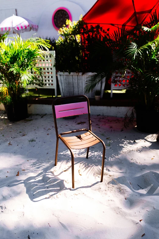 a small pink chair on a white sandy surface