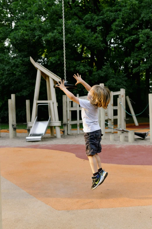 a boy swinging on a swing set and looking into the distance