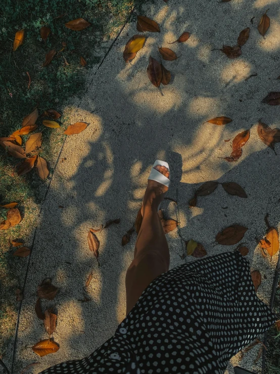 a person holding up a paper cup above leaves on the ground