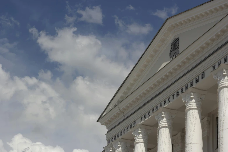 a large white building with many pillars against a cloudy sky