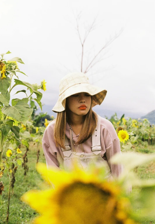 a woman wearing a hat standing in the middle of a sunflower field