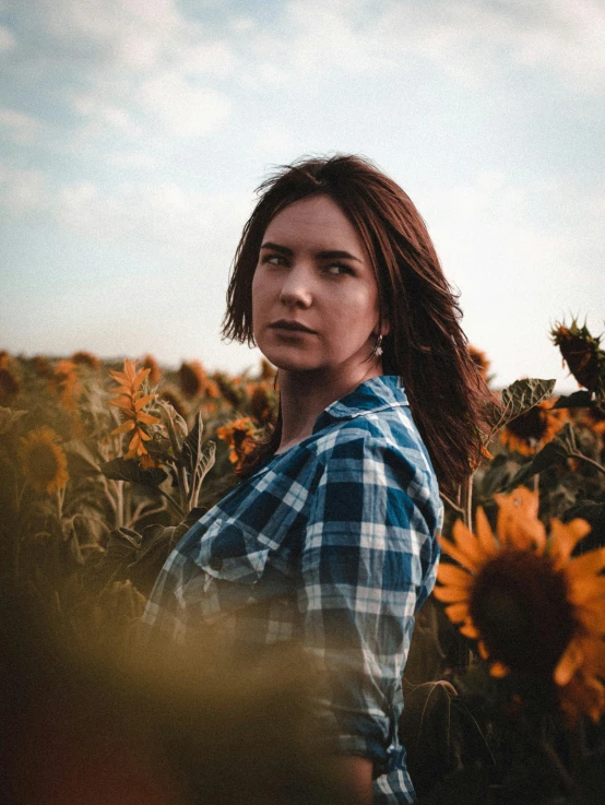 woman with brown hair standing in a field of sunflowers