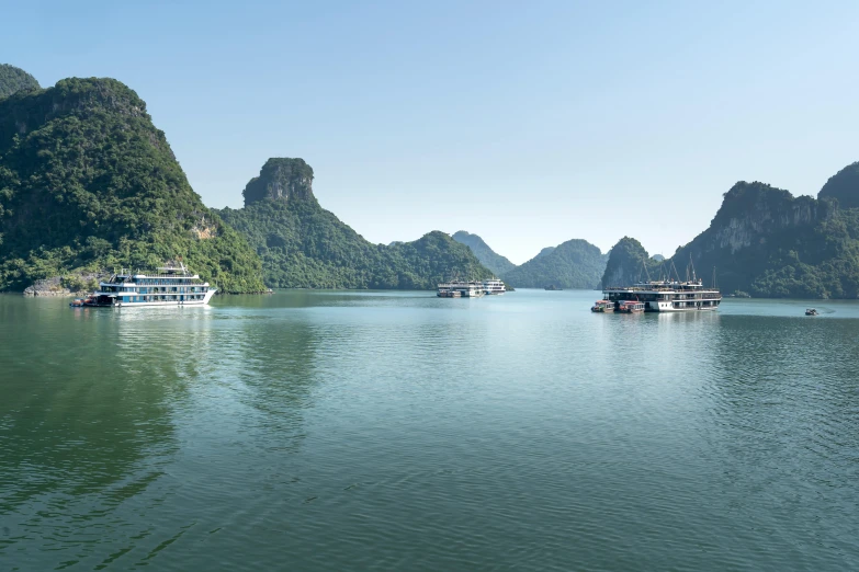 several boats on a lake with mountains and trees