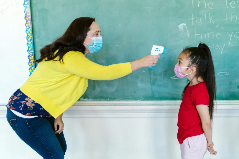 the teacher with mask teaching on the blackboard with two girls