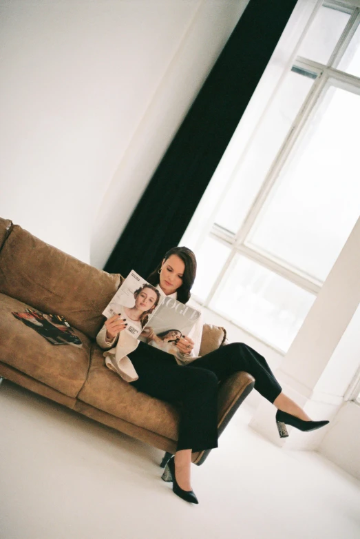 woman reading magazine sitting on couch in large room