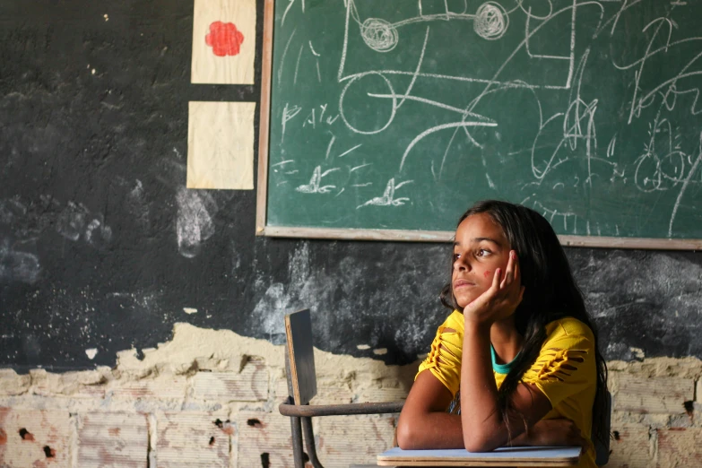 a girl is sitting in front of a chalkboard