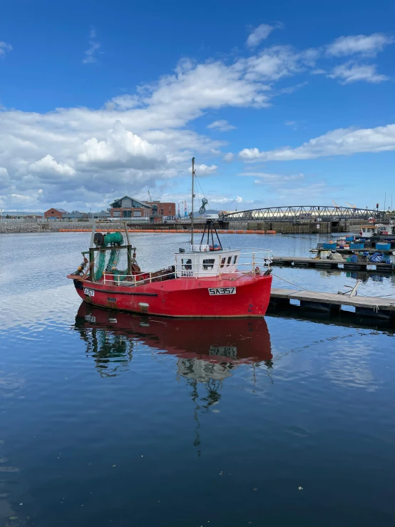 a red boat is sitting at a pier