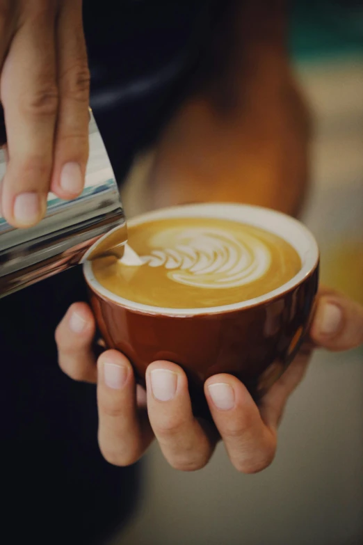 someone pouring a spoon into a cup of coffee