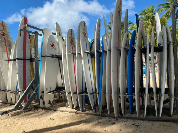 a group of surf boards stacked against a fence