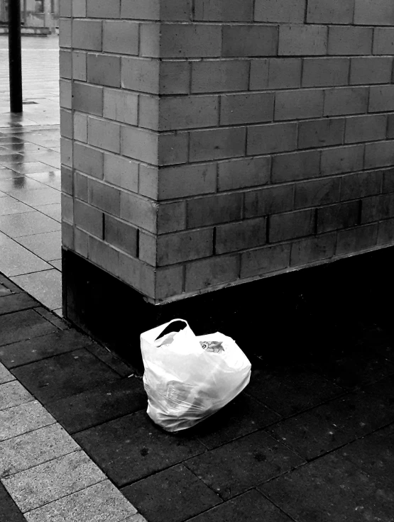 white paper bag sitting on a sidewalk near a building