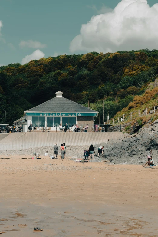 several people standing at the end of the beach looking in the sand