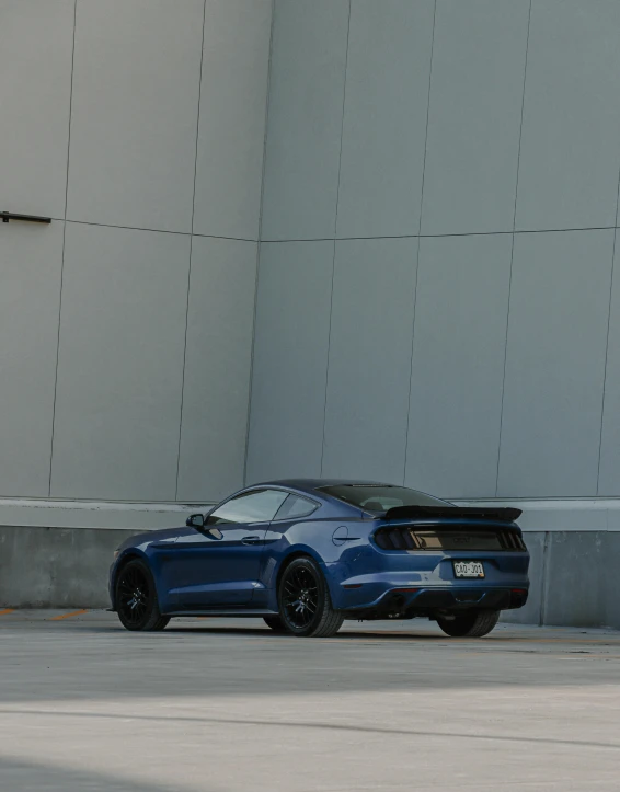 a blue mustang parked in front of a white building