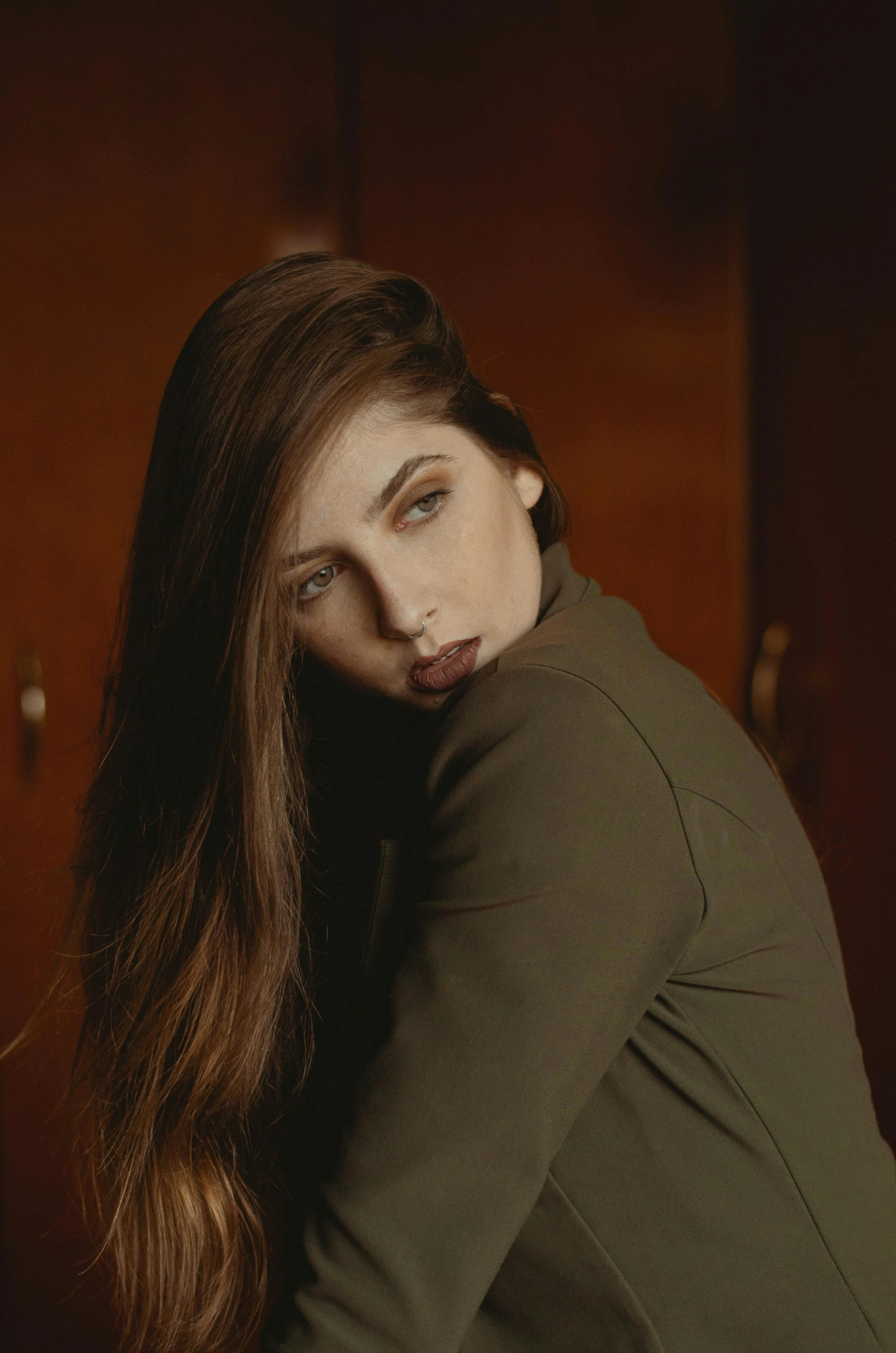 a woman with long hair and very long brown hair poses in a dark room