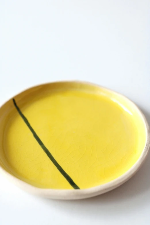 a yellow plate with green curved stripes sits on the table