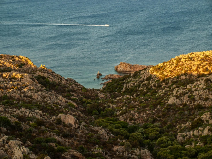 a boat floating along the water near some mountains