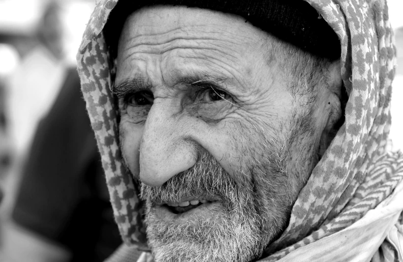 an elderly man with a head scarf is looking at the camera