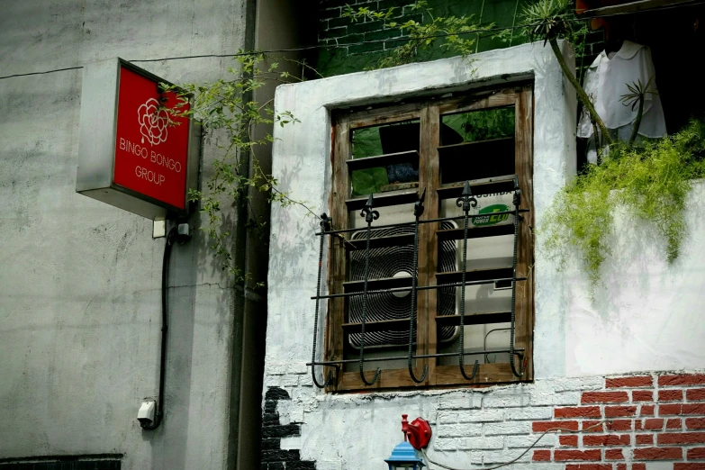 an old window on the side of a building with red and white signs on it