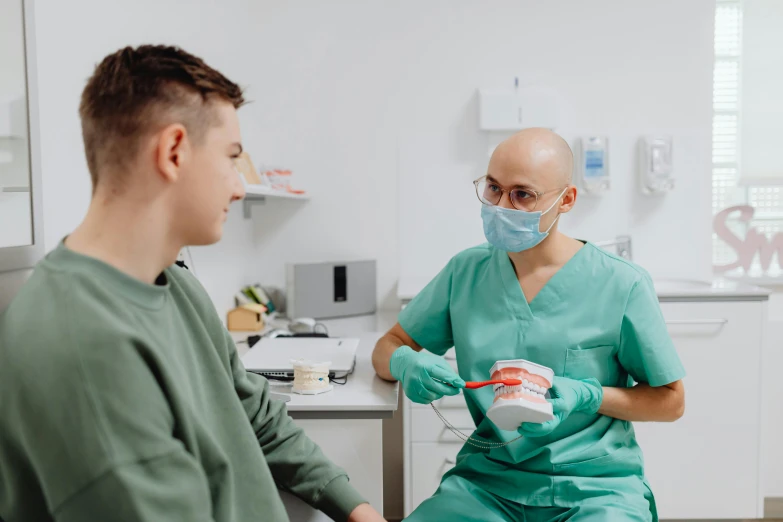 two medical personnel in green scrubs preparing to perform an operation