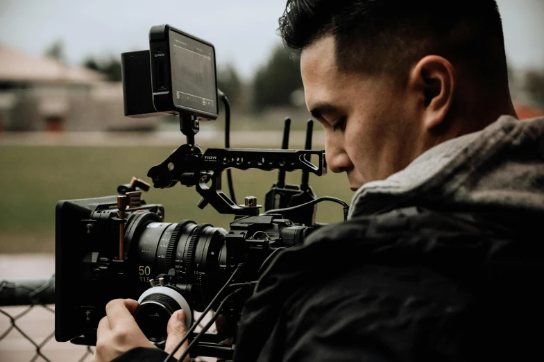 a man holding a camera while standing next to a metal fence