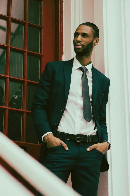 a man wearing a suit is standing near a window