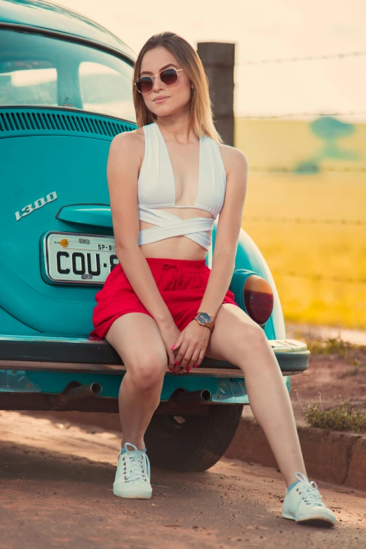 a woman sitting on a car wearing shades