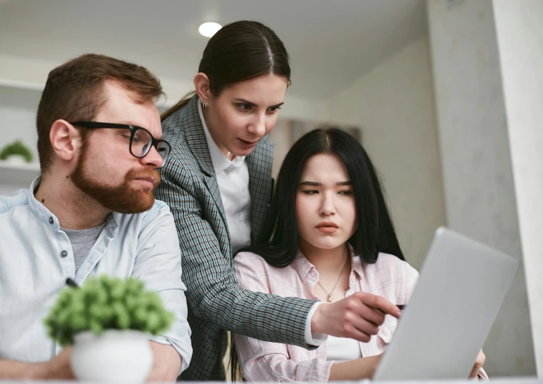 two people standing next to each other, working on a laptop