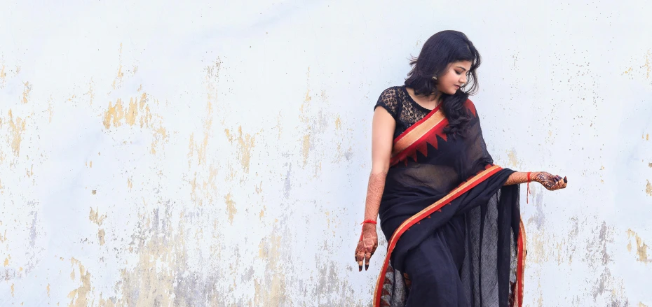 a woman wearing a black and red saree with a black hat