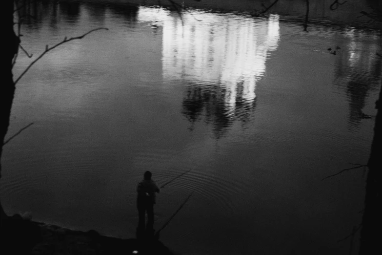 the person is standing near the water looking out to the river