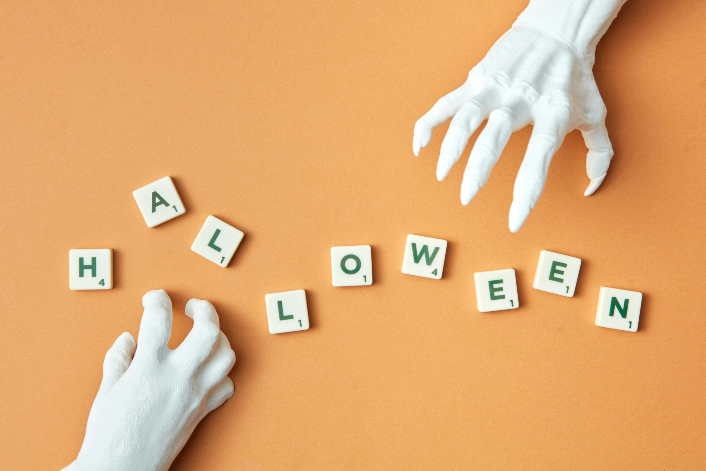 hands creating halloween word tiles in the air