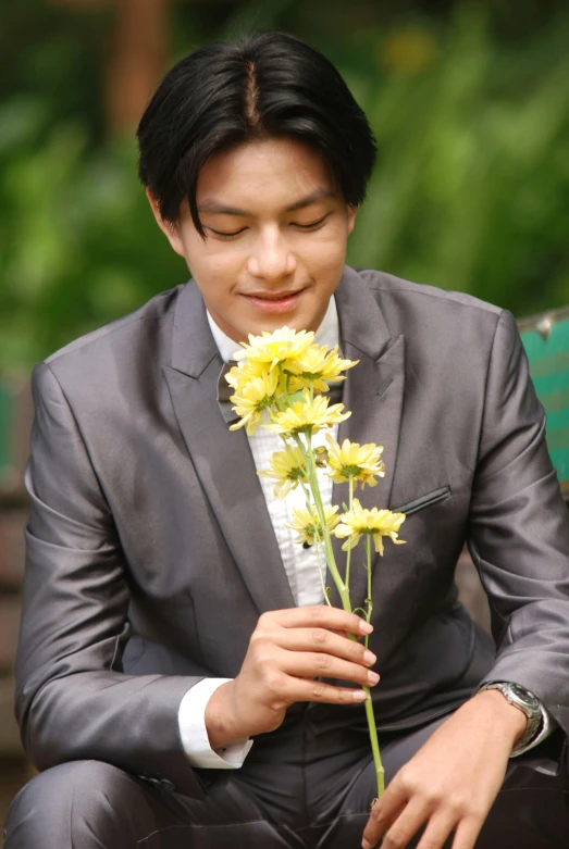 the man is wearing a suit holding flowers